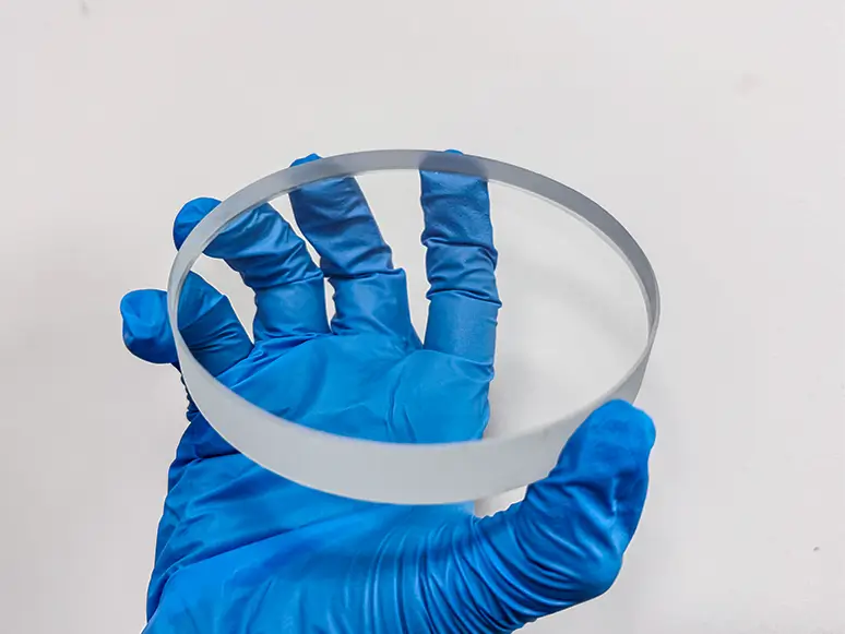 Hand holding a clear optical lens (optical flat)